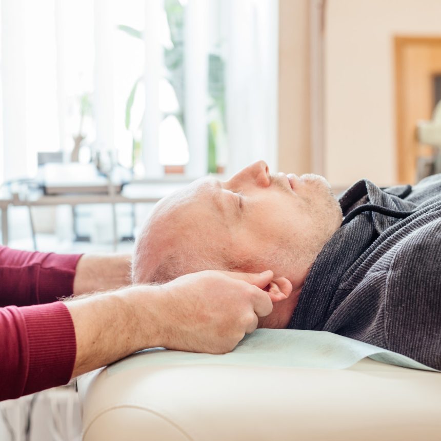 Male patient receiving cranial sacral therapy, lying on the massage table in CST osteopathy office